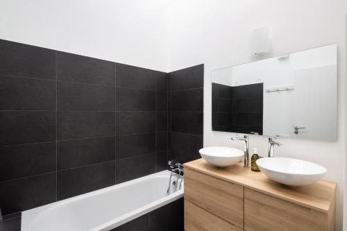 ein Badezimmer mit zwei Waschbecken, einer Badewanne und einem Spiegel in der Unterkunft Villa Emeraude by Cocoonr in Saint-Briac-sur-Mer