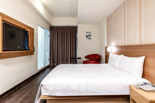 a hotel room with a bed and a television at Fish Hotel - Yancheng in Kaohsiung