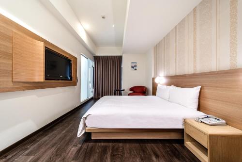 a hotel room with a bed and a tv at Fish Hotel - Yancheng in Kaohsiung