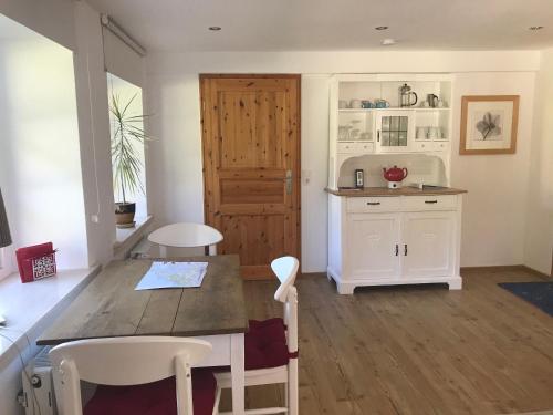 eine Küche mit einem Tisch, Stühlen und einer Tür in der Unterkunft Ferienwohnung Piesch in Glücksburg