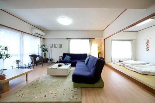 a living room with a blue couch and a bed at Exsaison house Kumoji in Naha