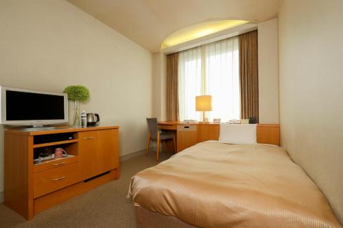 una camera d'albergo con letto e scrivania con TV di Hotel Grand Vert Gizan a Gifu