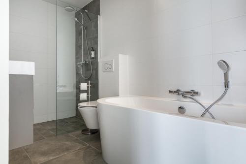 a bathroom with a bath tub and a toilet at Hotel Victoria in Bergen aan Zee