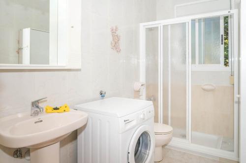 een witte badkamer met een wasmachine en een wastafel bij Bungalows Canadá Alquileres Vacacionales in Calpe