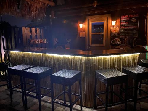 a bar with four stools in a bar with lights at The Cabanas Guesthouse & Spa - Gay Men's Resort in Fort Lauderdale
