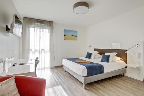 a white bedroom with a bed and a red couch at All Suites Appart Hôtel - Bordeaux - Pessac in Pessac