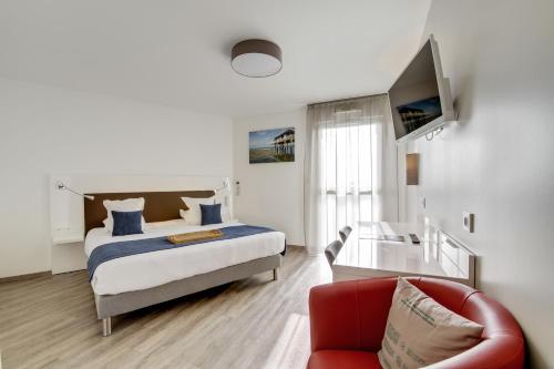 a bedroom with a bed and a red couch at All Suites Appart Hôtel - Bordeaux - Pessac in Pessac