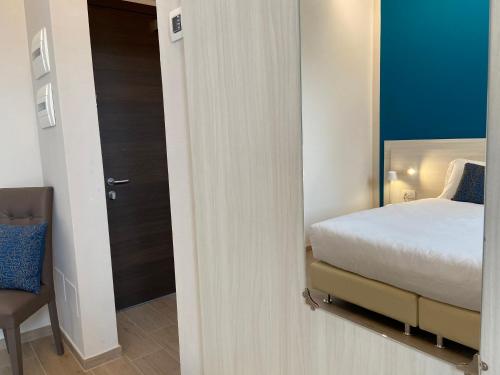 a bedroom with a bed and a door with a chair at Palazzo Marignano Hotel in Melegnano