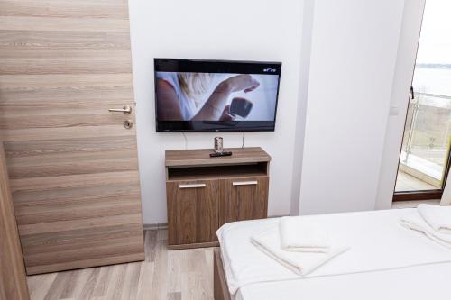 a bedroom with a tv on a wall next to a door at Summerland Sea View Apartment in Mamaia