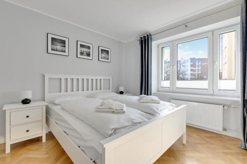 ein weißes Schlafzimmer mit einem weißen Bett und einem Fenster in der Unterkunft Wave Apartments - Grobla Old Town in Danzig
