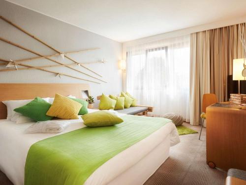 a bedroom with a large bed with green and yellow pillows at Novotel Gdansk Centrum in Gdańsk