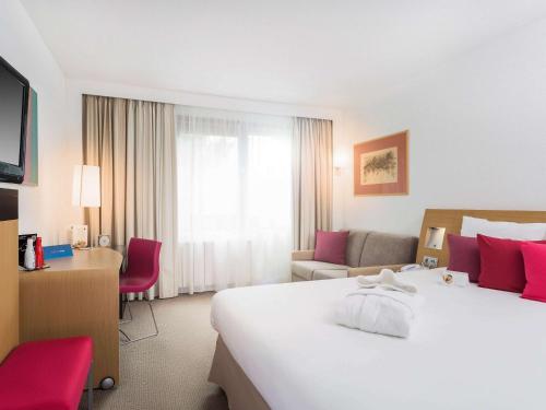 a hotel room with a large white bed and a desk at Novotel Warszawa Airport in Warsaw