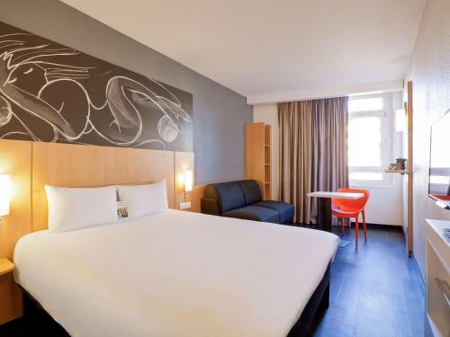 een hotelkamer met een groot bed en een stoel bij ibis Annecy Centre Vieille Ville in Annecy
