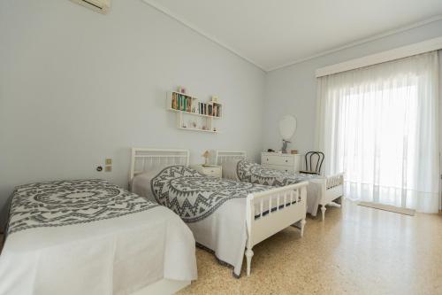 a white bedroom with two beds and a window at villa nicol in Korinthos