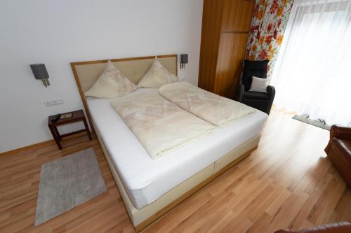 a white bed in a room with a wooden floor at Ferienwohnungen Angermaier in Flattach