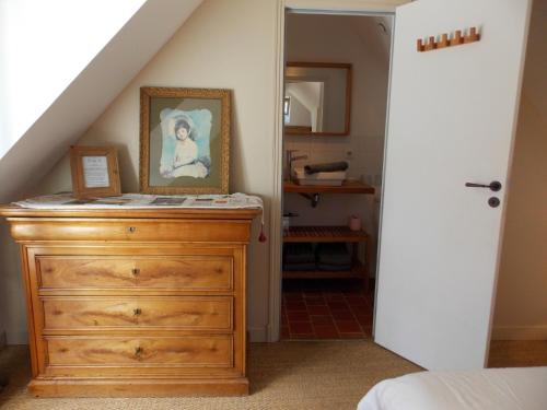 a bedroom with a dresser with a painting on it at Domaine du Gué du Roi in Cléry-Saint-André