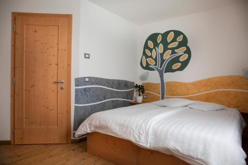 a bedroom with a bed with a tree on the wall at Baita Scaia in Cogolo
