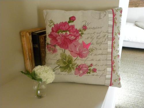 a pillow on a table with a vase of flowers at Domaine du Gué du Roi in Cléry-Saint-André