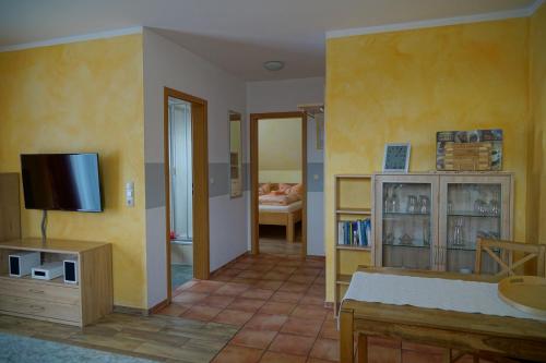 sala de estar con paredes amarillas y TV en Ferienwohnung Koserow en Ostseebad Koserow