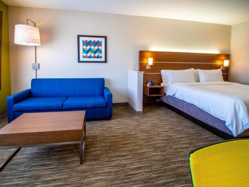 um quarto de hotel com uma cama e um sofá azul em Holiday Inn Express & Suites - Oklahoma City Airport, an IHG Hotel em Oklahoma City