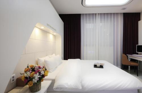 een hotelkamer met een wit bed en bloemen erop bij Urban Stay Hotel in Gwangju