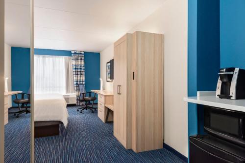 a hotel room with a bedroom with a bed and a mirror at Holiday Inn Express Dumfries-Quantico by IHG in Dumfries