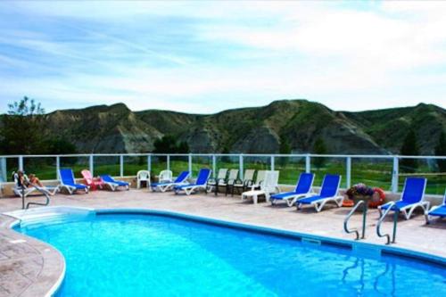 una piscina con sillas azules y montañas de fondo en Paradise Canyon Golf Resort, Luxury Condo U409, en Lethbridge