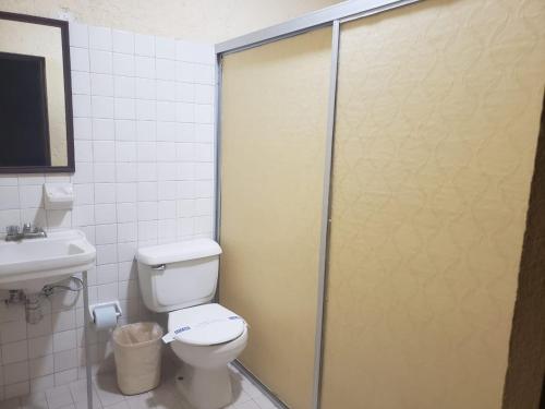 a bathroom with a toilet and a glass shower door at Hotel Del Valle in El Naranjo