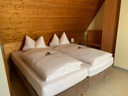 a large bed with white sheets and pillows at Gästehaus an der Rheinbrücke in Altlußheim