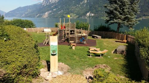 a park with a playground in the grass next to a lake at Holiday apartment #103 on Walensee in Unterterzen