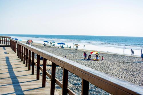a boardwalk on a beach with people and umbrellas at BEACHFRONT Escape - Cozy Studio in Tijuana