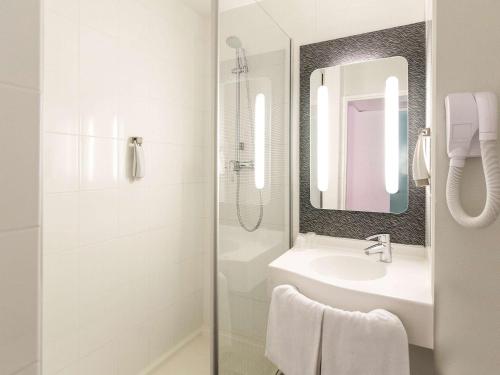 a bathroom with a sink and a shower with a mirror at ibis Limoges Nord in Limoges