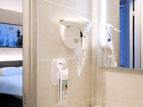 La salle de bains est pourvue de 2 sèche-cheveux sur le mur. dans l'établissement ibis Styles Rouen Nord-Barentin, à Barentin