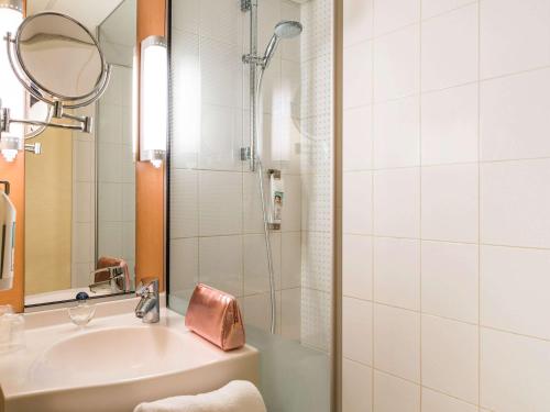 a bathroom with a sink and a shower with a mirror at ibis Paris Pont de Suresnes Longchamp in Suresnes
