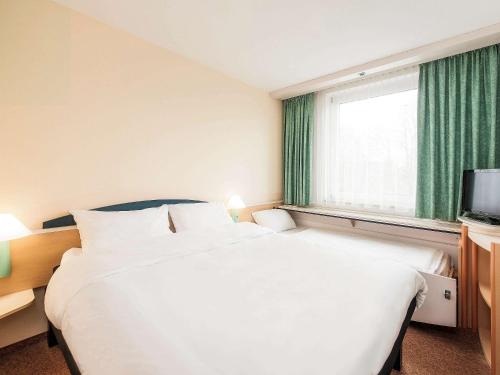 Habitación de hotel con cama grande y ventana en ibis Paderborn City en Paderborn