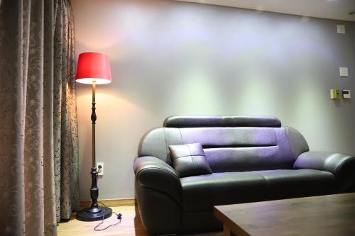a living room with a leather couch and a red lamp at Residence Hotel Lamia in Daejeon