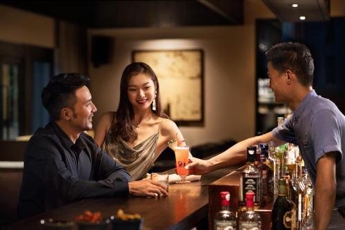 a group of people sitting at a bar at Raffles Hainan Clear Water Bay in Sanya