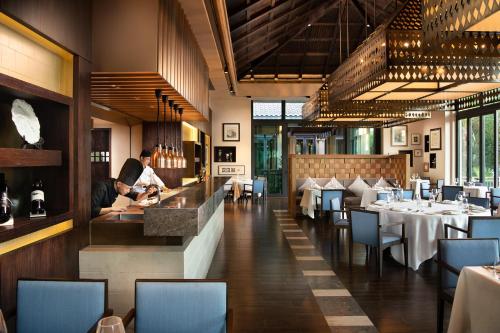 a restaurant with people sitting at a counter and tables at Raffles Hainan Clear Water Bay in Sanya