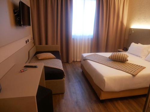 
a hotel room with a bed and a desk at First Hotel Malpensa in Case Nuove
