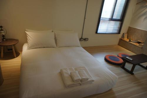 1 dormitorio con 1 cama blanca y 2 toallas en Through A Path, en Tainan