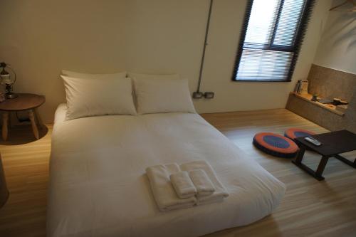a bedroom with a white bed with two towels on it at Through A Path in Tainan