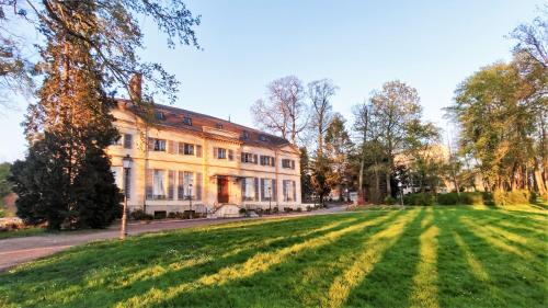 una casa grande con un campo de hierba delante de ella en La Maison Verneuil, en Paray-le-Monial