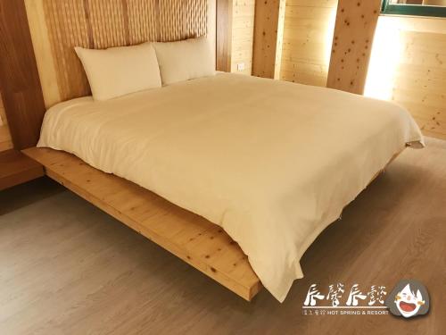 a bed in a wooden room with a white bedspread at 沐馨溫泉民宿 in Jiaoxi