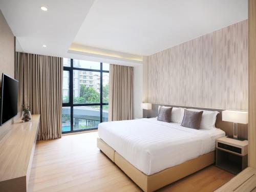a bedroom with a white bed and a large window at Arden Hotel and Residence by At Mind in Pattaya Central