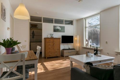 a living room with a table and a tv at Appartement Torenzicht - Leeuwarden in Marssum