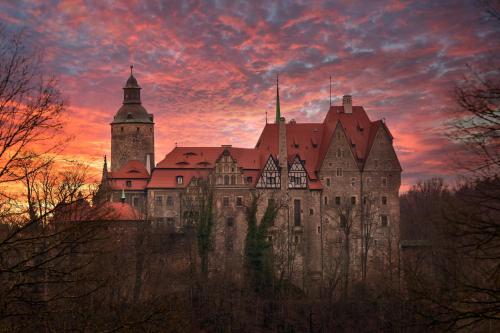 a large castle with a sunset in the background at Zamek Czocha in Leśna