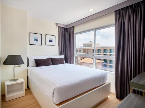 1 dormitorio con cama grande y ventana grande en The Grass Serviced Suites en Pattaya centro