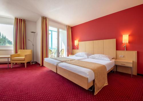 Grand Hotel et Centre Thermal d'Yverdon-les-Bains في إفردون-لو-بان: غرفة نوم بسرير كبير وجدار احمر