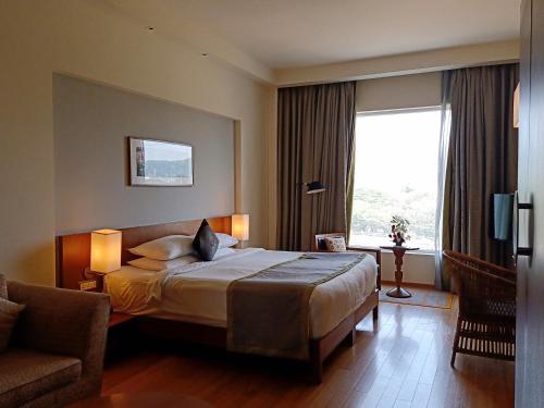 a hotel room with a bed and a chair and a window at The Park Navi Mumbai in Navi Mumbai