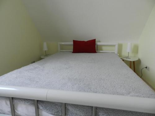 um quarto com uma cama com uma almofada vermelha em Ferienwohnung Burgenblilck em Weinheim